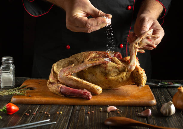 istock A skilled chef carefully seasons a whole duck with salt while resting it on a rustic wooden cutting board. The warm kitchen ambiance and kitchen tools enhance the culinary creativity at play. 2198521881