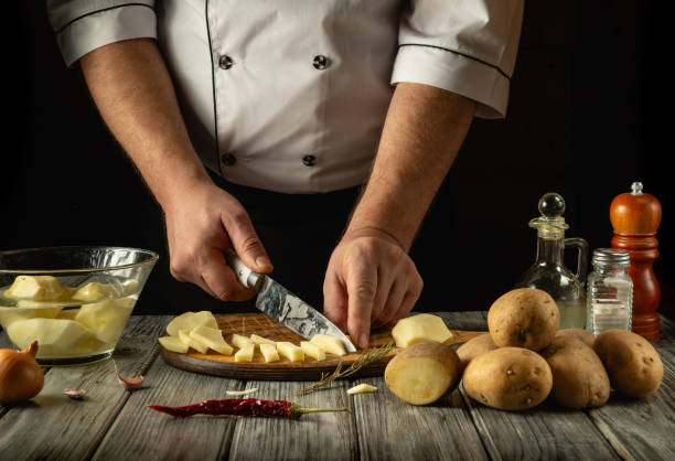istock A skilled chef engages in culinary preparation, chopping fresh potatoes with precision. Various ingredients are arranged artistically on a wooden countertop, blending rustic charm and gastronomy 2198521887