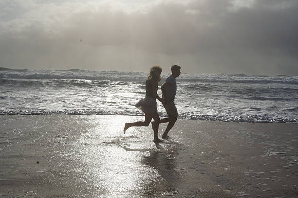 Loving couple playing on ocean beach. Couple of lovers on a romantic date at the beach at sunset