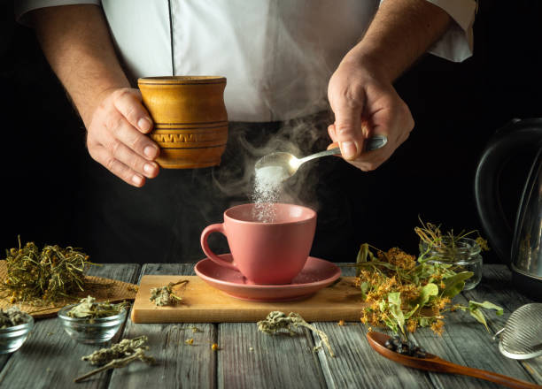 istock Hands skillfully blend dried herbs and sugar, creating a fragrant herbal drink in a warm kitchen. An inviting atmosphere, with natural elements surrounding a charming pink cup awaiting its infusion 2198522091