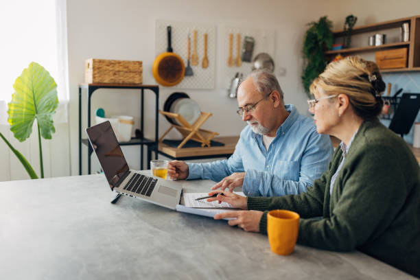 istock A focused senior couple sits at a kitchen table and uses a laptop while managing household finances and making financial plans for their retirement income 2198523028