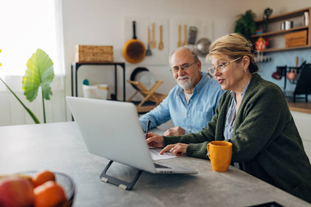 istock Senior couple doing home admin, interacting with appropriate technology such as a laptop. Senior people think about themselves, digest information, think about next steps and plan 2198523060