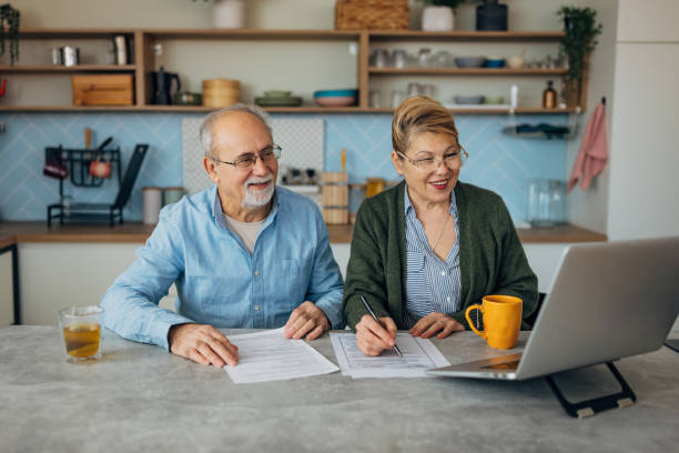 istock Senior man and woman looking at financial document and bills, using the internet to pay mortgage loans 2198523103