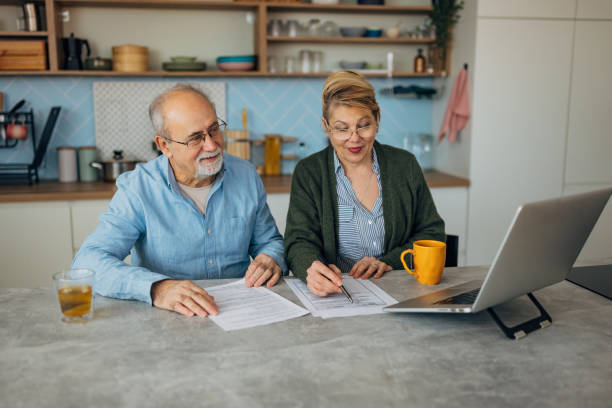 istock Senior couple looking at financial document and bills, using the internet to pay mortgage loans 2198523192