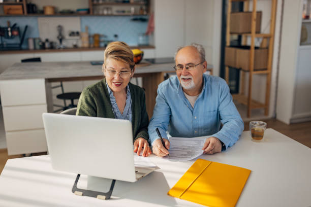 istock Smiling senior couple manage family budget, sorting out papers, make payments through electronic bank using laptop 2198523858