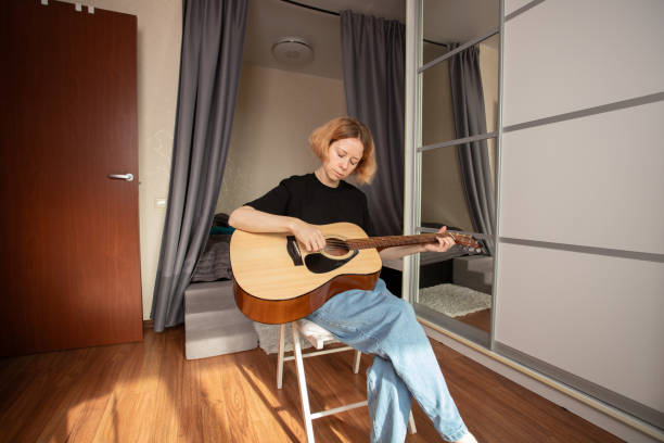 istock music lessons, Woman learning guitar, developing guitar skills, working on fretboard technique, engaged in musical education 2198535441