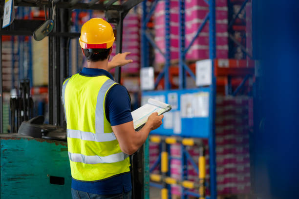istock Warehouse supervisor in reflective safety gear walking through a distribution warehouse, inspecting stock inventory. Ensuring quality control, supply chain efficiency, and logistics management for global business and freight transportation. 2198540414