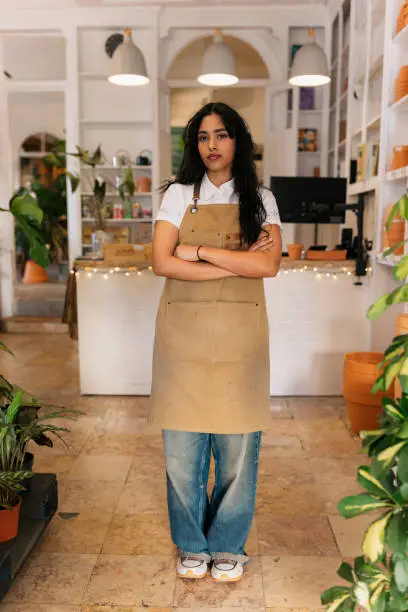 Young confident hispanic florist posing with arms crossed in her flower shop Young confident hispanic florist posing with arms crossed in her flower shop