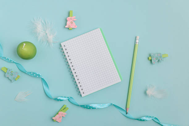 istock A pastel Easter scene featuring a bouquet of pink tulips adorned with a delicate blue ribbon, a notebook, wooden rabbit figurines, and soft feathers. Perfect for celebrating the Easter holiday. 2198541016