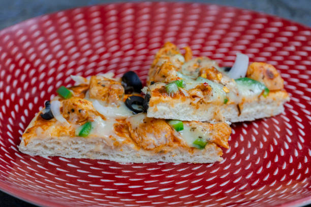 istock Freshly sliced B.B.Q pizza with olives, mozzarella, and chicken on a red plate with sauce 2198543998