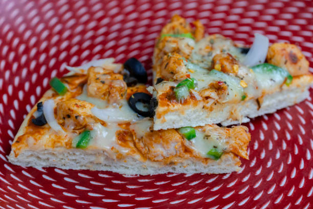 istock Freshly sliced B.B.Q pizza with olives, mozzarella, and chicken on a red plate with sauce 2198544018