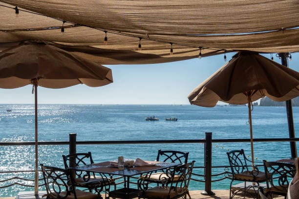 istock A restaurant by the ocean with tables, chairs, and umbrellas 2198544036