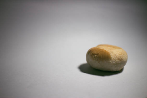 Side view of a golden-brown bakpia pastry on a white background, showcasing its round shape and soft texture.