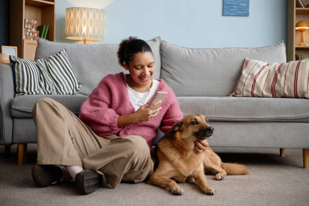 istock Smiling Woman Sitting on Couch with Dog and Using Phone 2198546123