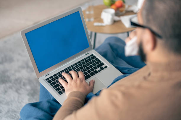istock Person Using Laptop with Blue Screen, Wrapped in Blanket, Resting on Couch Comfortably 2198548886