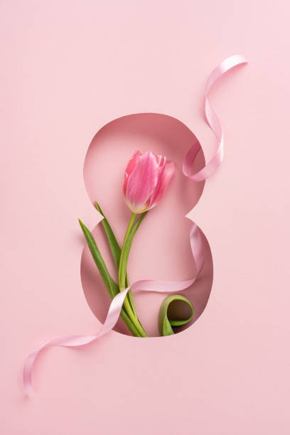 istock Vibrant vertical pink tulip with its leaves placed inside an eight-shaped cutout and decorative ribbon 2198550763