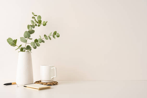 istock Minimalistic arrangement with a white vase of eucalyptus leaves, coffee mug, and notepad on a clean surface. Highlights cozy, natural, and elegant decor elements for creative and simple living spaces 2198550799
