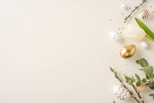 istock Decorative Easter scene featuring golden eggs, green leaves, white tulip, and festive organic elements highlighted in a minimalist layout on a pale background 2198550811