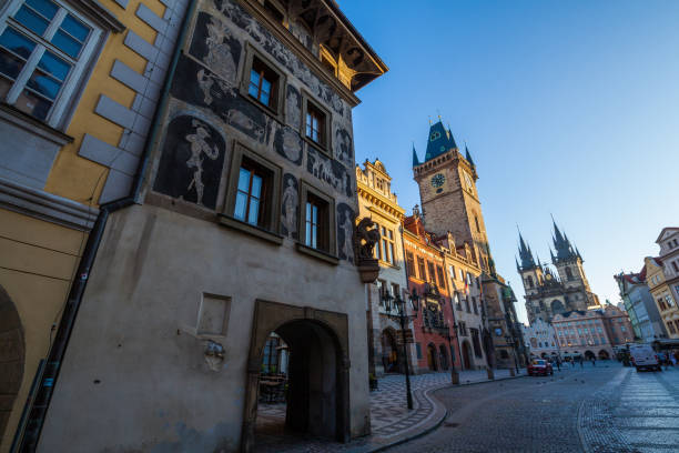 istock A cobblestone square featuring historic buildings with decorative facades, including a prominent clock tower and spired church, under a clear blue sky with sunlight. 2198553444