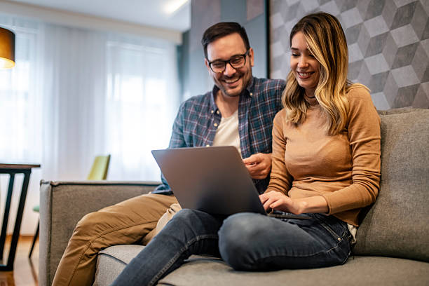 istock Happy Couple Relaxing at Home Using a Laptop on Couch 2198553935