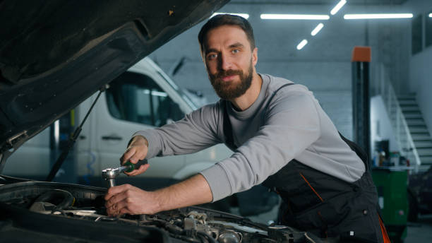 istock Caucasian man technician worker repairman mechanic check fix problem under open automobile hood smiling happy male guy in uniform use spanner key instrument repair car in garage auto service station 2198554061