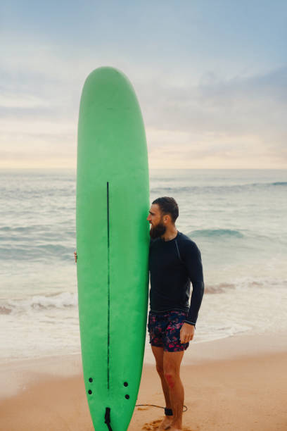 istock Surfer holding surf board on the beach at sunset. Happy man guy having fun doing extreme sport. 2198555321