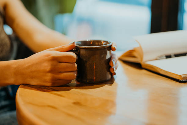 istock Woman holding a coffee mug while reading in a cafe 2198556109