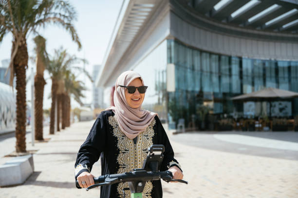 istock Smiling Arabic woman using electric scooter in the downtown 2198557558