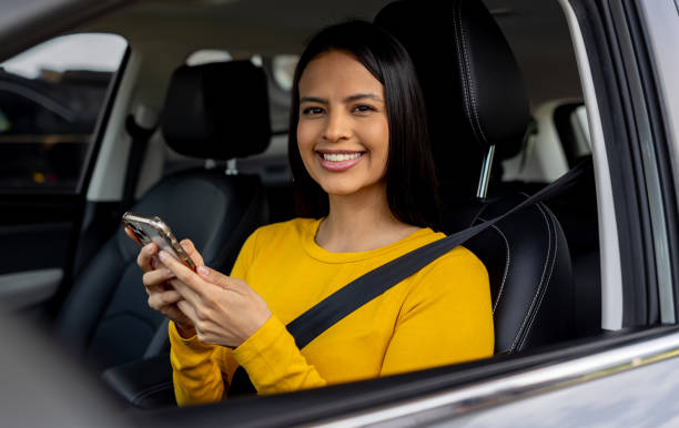 istock Happy woman sitting in her car and using her cell phone while parked 2198562581