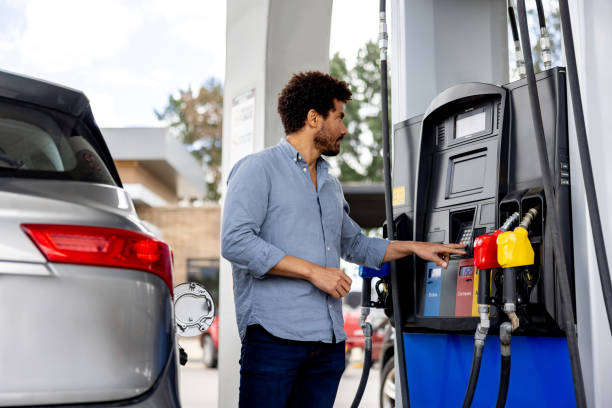 istock Man at a gas station pressing a button on the machine while refueling his car 2198562633