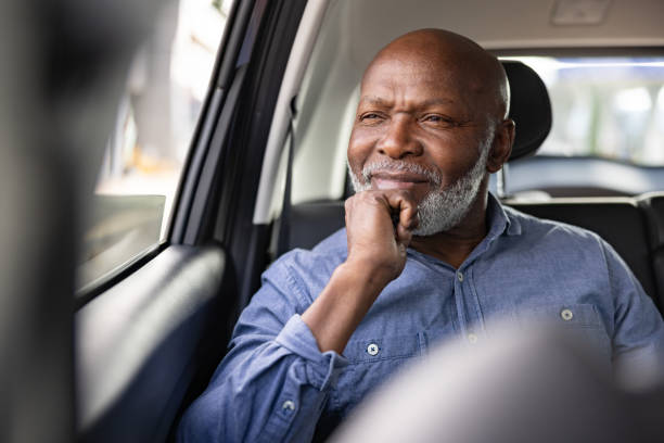 Senior man riding on a crowdsourced taxi and looking through the window
