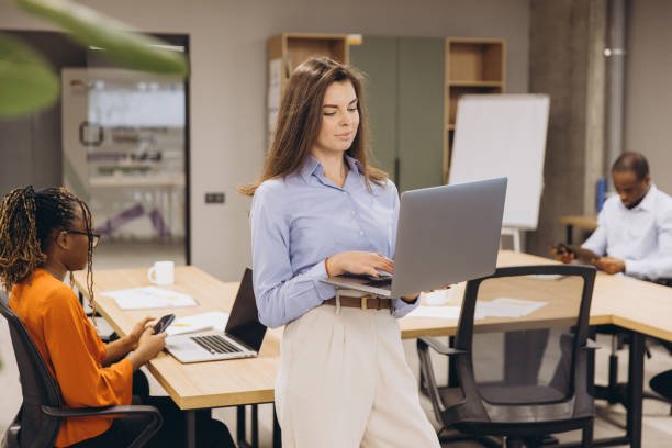 istock Professional female working on laptop amid collaborative workspace, colleagues engaged nearby 2198564081