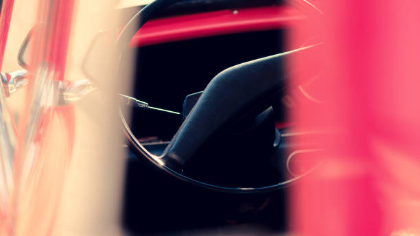 A close up of a steering wheel with a chain hanging from it. The chain is attached to a metal bracket on the steering wheel. The image has a vintage feel to it