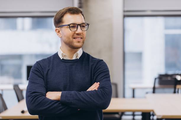 istock Confident businessman standing with crossed arms, radiating professional demeanor inside modern workspace with clean design 2198564723