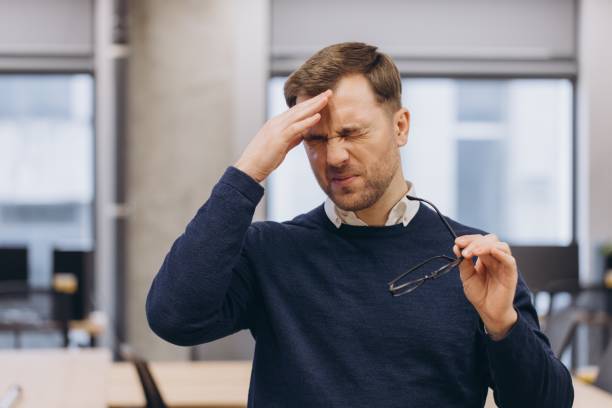 istock Businessman having a bad headache at work, touching his forehead with hand and holding glasses 2198565285