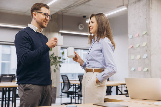 istock Colleagues conversing, holding coffee mugs near workspace with contemporary design 2198565382