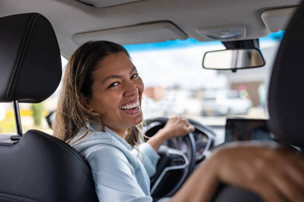 istock Happy woman smiling in a car while looking back at the passenger seat 2198565836