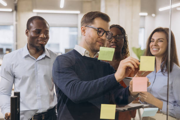 istock Diverse group of professionals engaging in a collaborative brainstorming session, using sticky notes on a glass wall in a modern office environment 2198568177