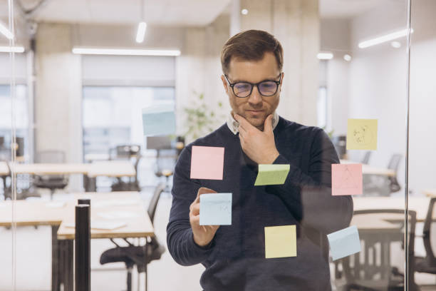 istock Businessman analyzing ideas on colorful sticky notes in a modern office setting, reflecting on strategic planning and innovation 2198568328