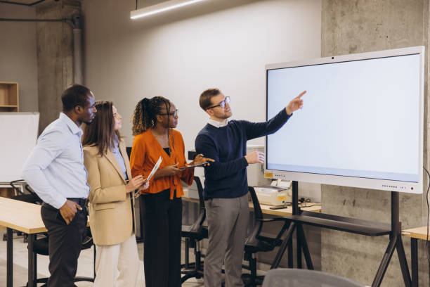 istock Diverse group of professionals engaging in a collaborative discussion around a digital whiteboard in a modern office setting 2198568509