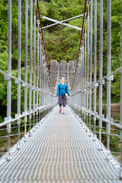 istock Woman walking on a suspension bridge in the mountains 2198568574