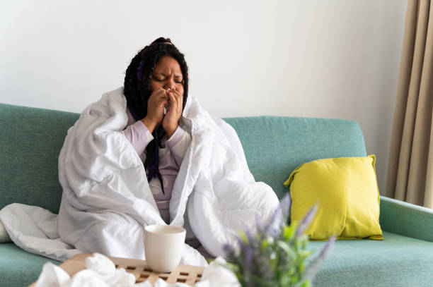 istock Sick young woman blowing her nose on the sofa at home 2198568624