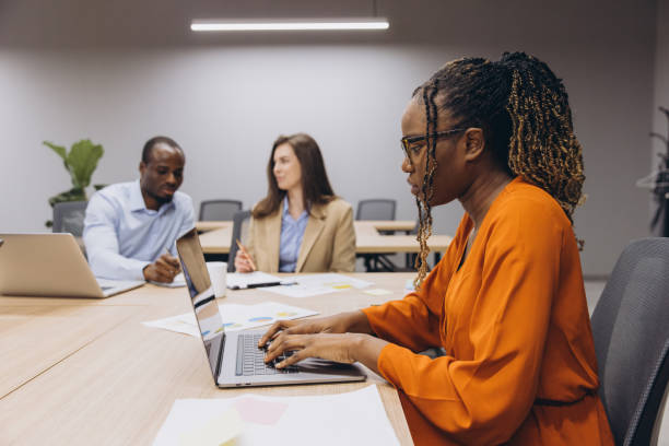 istock Professionals engaging in a collaborative meeting, using laptops and discussing business strategies in a contemporary office environment 2198570542