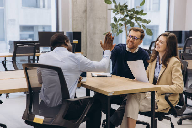 istock Diverse business team in a modern office environment celebrating success with a high five, showcasing teamwork and collaboration in a professional setting 2198570666
