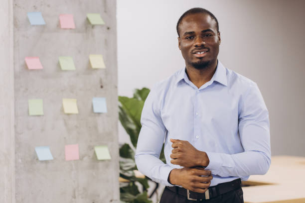 istock African american professional beaming, standing near colorful sticky notes in sleek workspace, highlighting collaborative workplace environment 2198570828