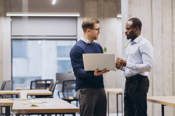 istock Businesspeople conversing near large windows, sharing insights in modern workspace with natural light and sleek design 2198570924