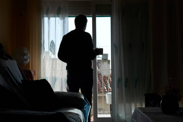 istock Silhouette of a man holding a coffee cup by the balcony. 2198570992