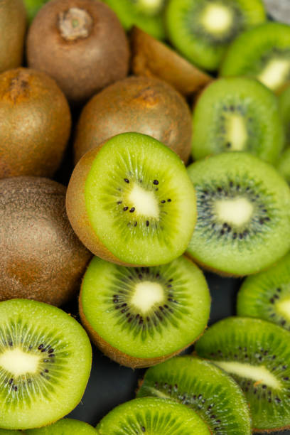 Fresh kiwi fruit, many whole and sliced kiwi.
