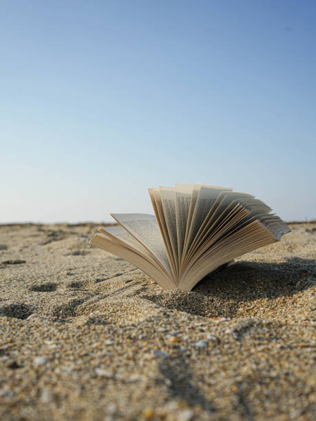 istock Open book pages on a sand ground at the beach 2198571683