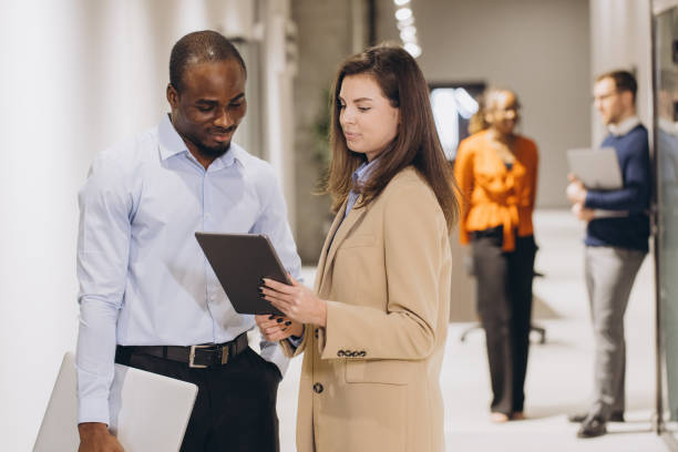 istock Professional colleagues analyzing project details, sharing insights through digital tablet in modern office hallway setting 2198573245